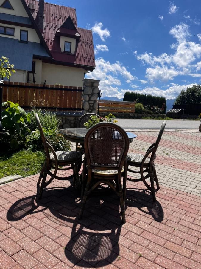 Wiklinowe krzesła i stolik na patio przed domem w słońcu